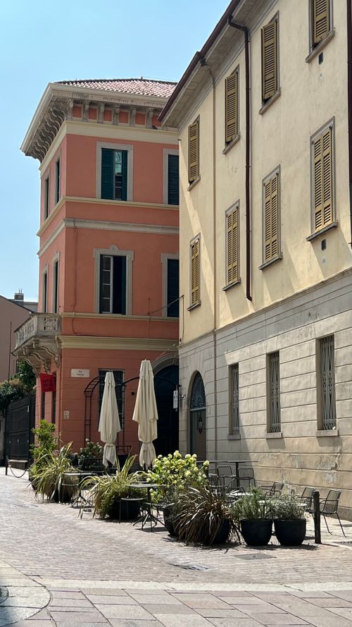 Free Picturesque street in Italy with historic buildings and outdoor seating, capturing authentic Italian charm. Stock Photo