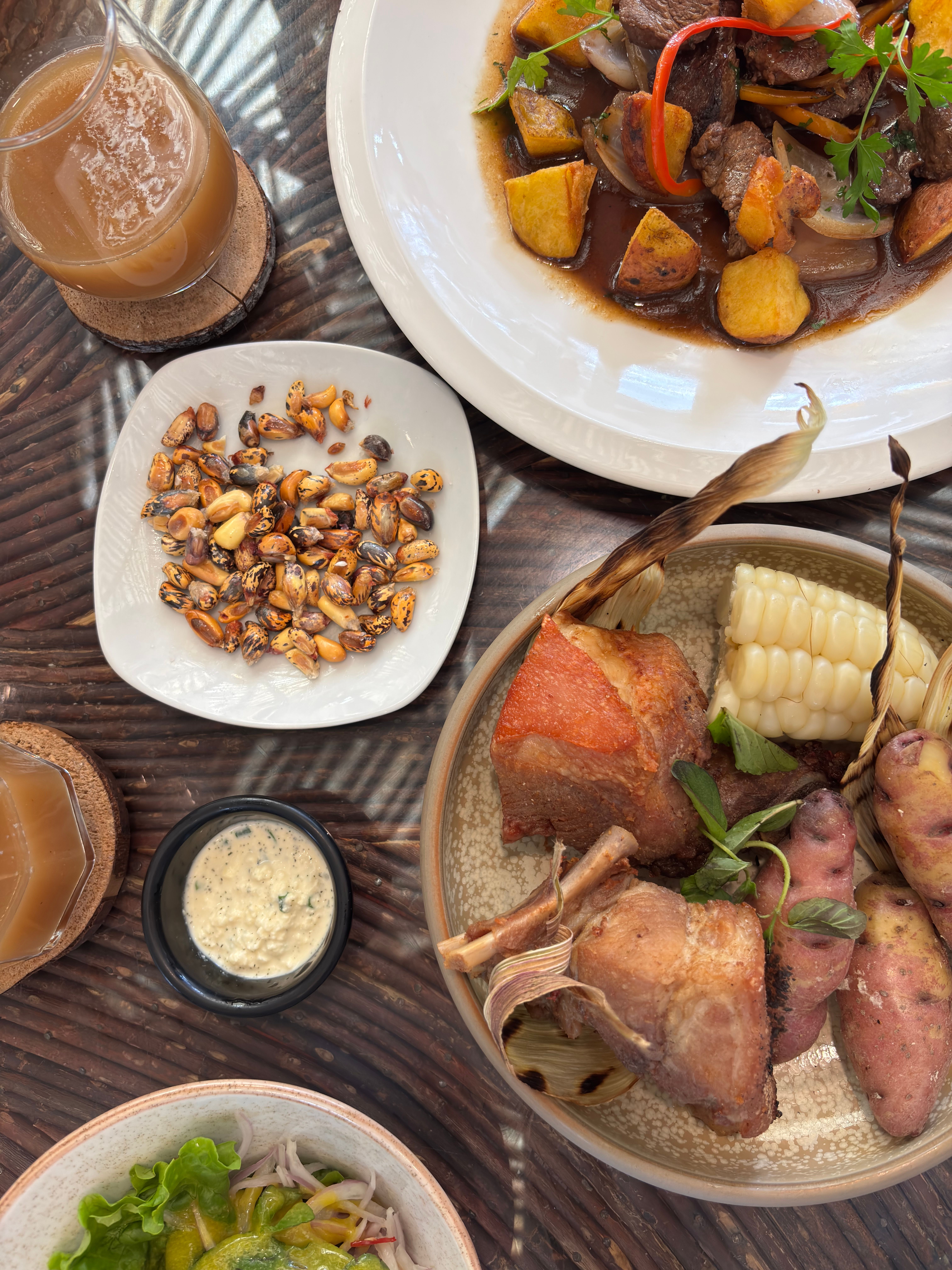 Vue de dessus : maïs grillé en coupelle, viande rôtie, épi de maïs géant et pommes de terre andines violettes