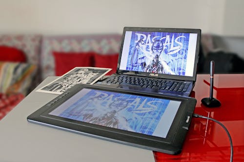 Tablet Beside Laptop on Red Table
