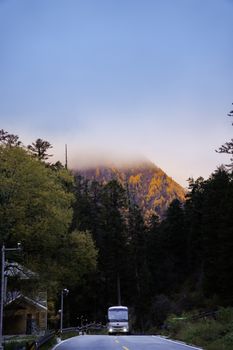 A quiet mountain road in Sichuan, China, at sunrise with mist-covered peaks.