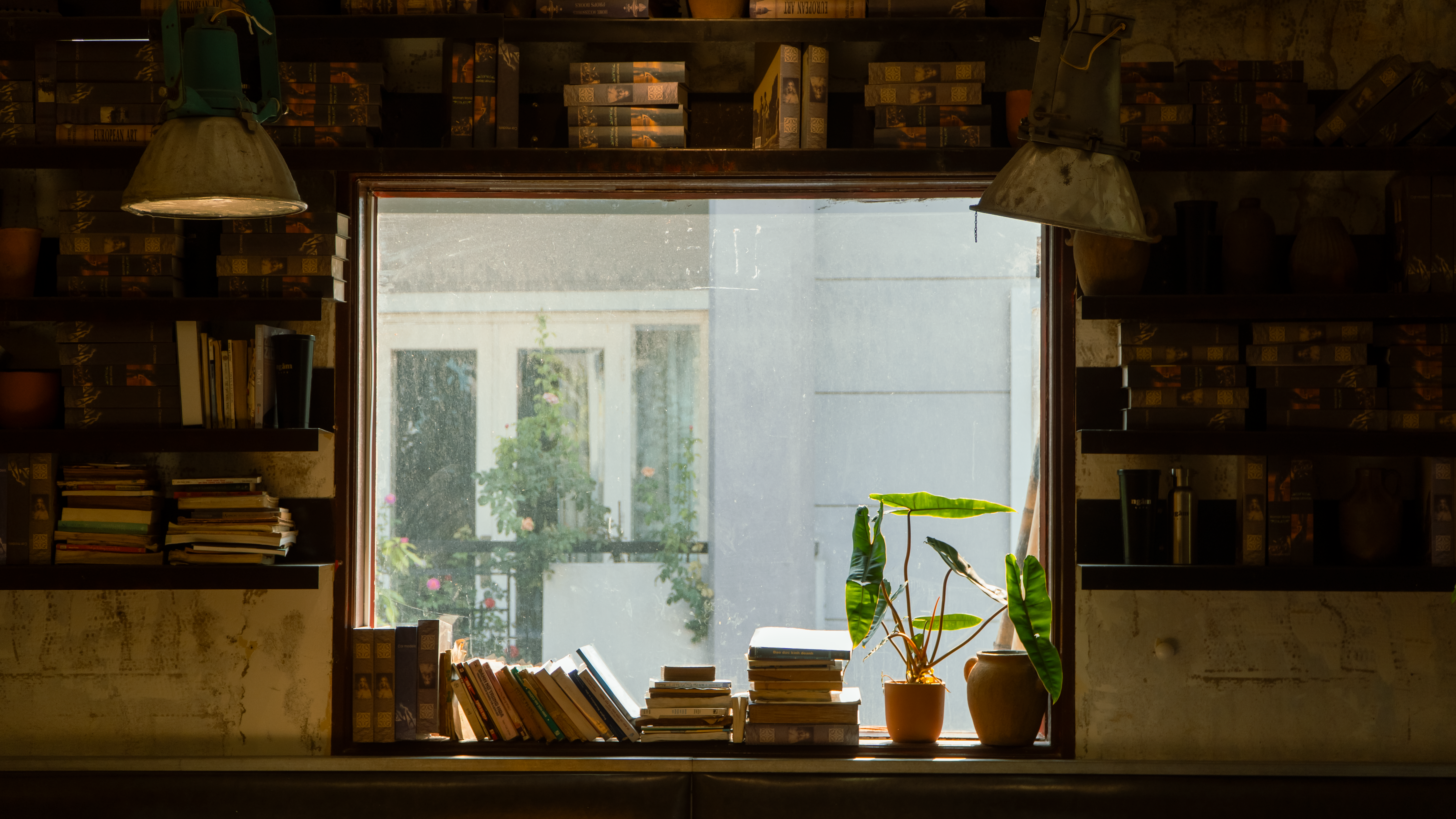 A person sitting in a cozy home office nook, looking out a window, with a notebook and a plant nearby