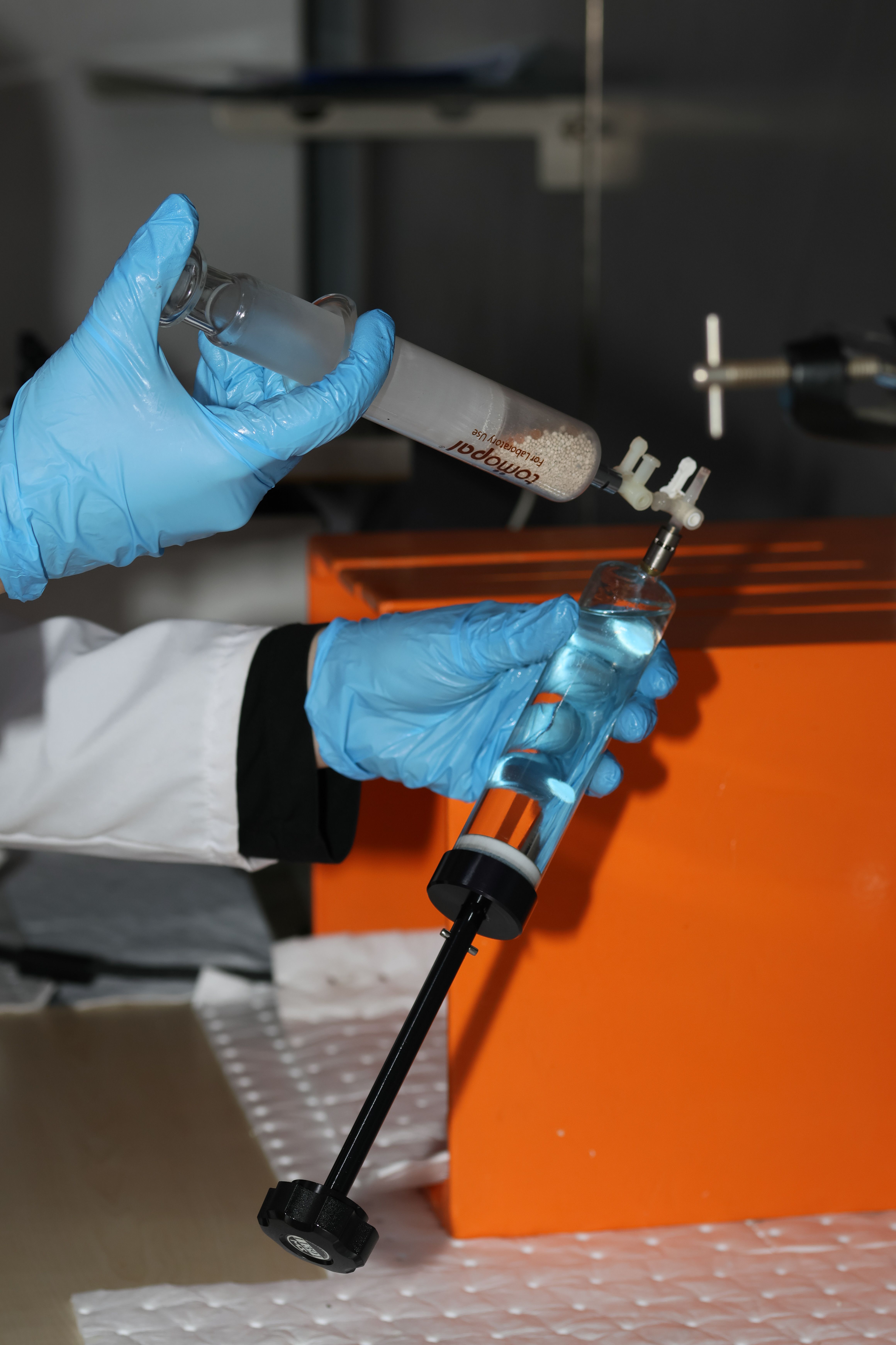 Scientist handling lab equipment wearing gloves. Experimentation in progress.