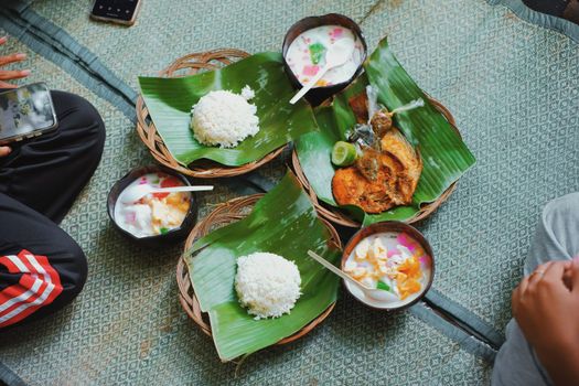 Enjoy a traditional Indonesian meal featuring rice, fish, and desserts served on banana leaves.
