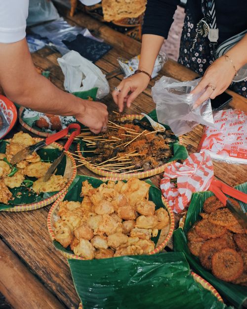 Free Close-up of traditional Indonesian street food stalls in Bandung with locals selecting snacks. Stock Photo