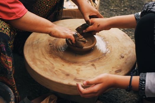 Close-up of hands shaping clay on a potter's wheel outdoors in Java, Indonesia.