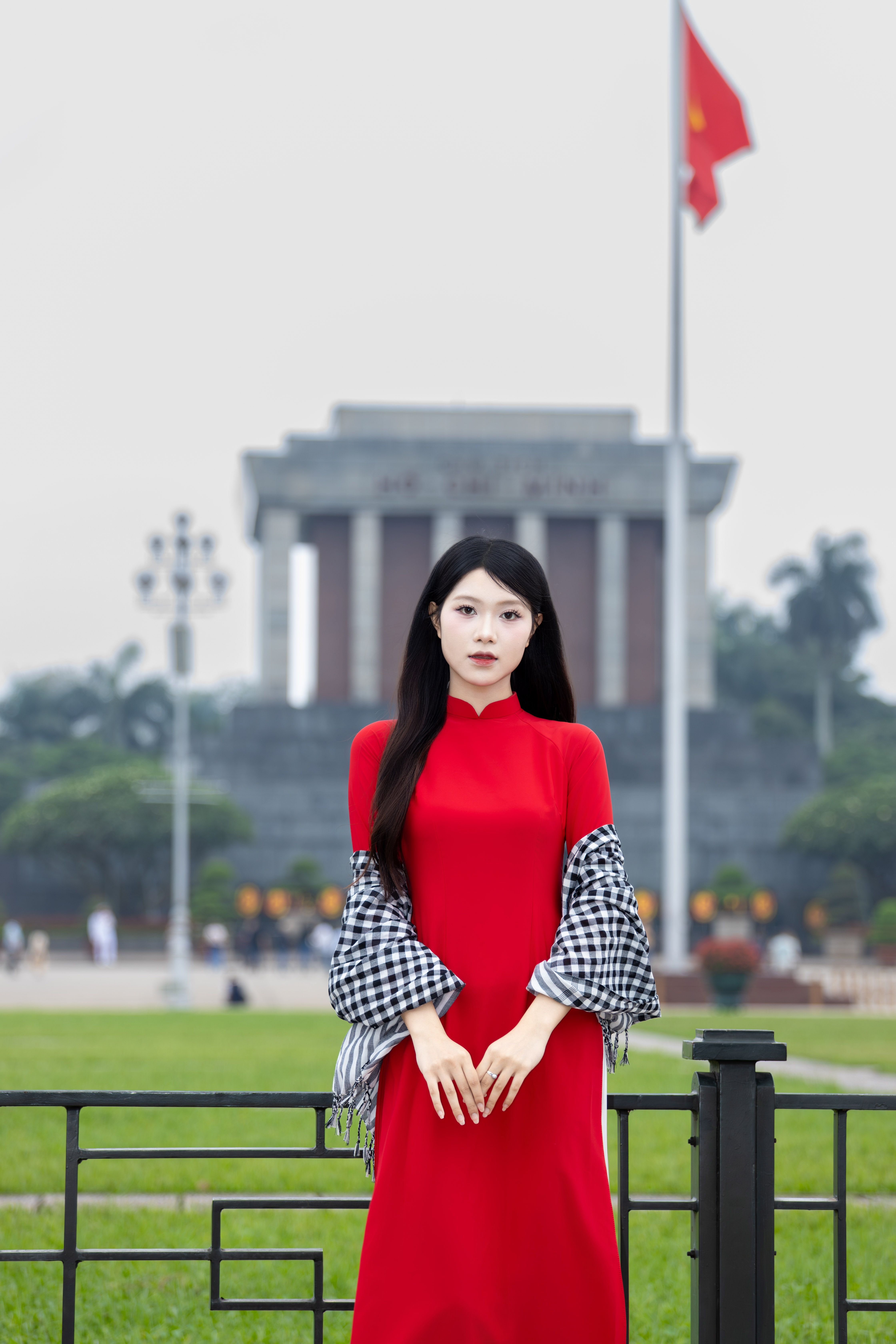 Woman in red áo dài at Ho Chi Minh Mausoleum, Hanoi, Vietnam.