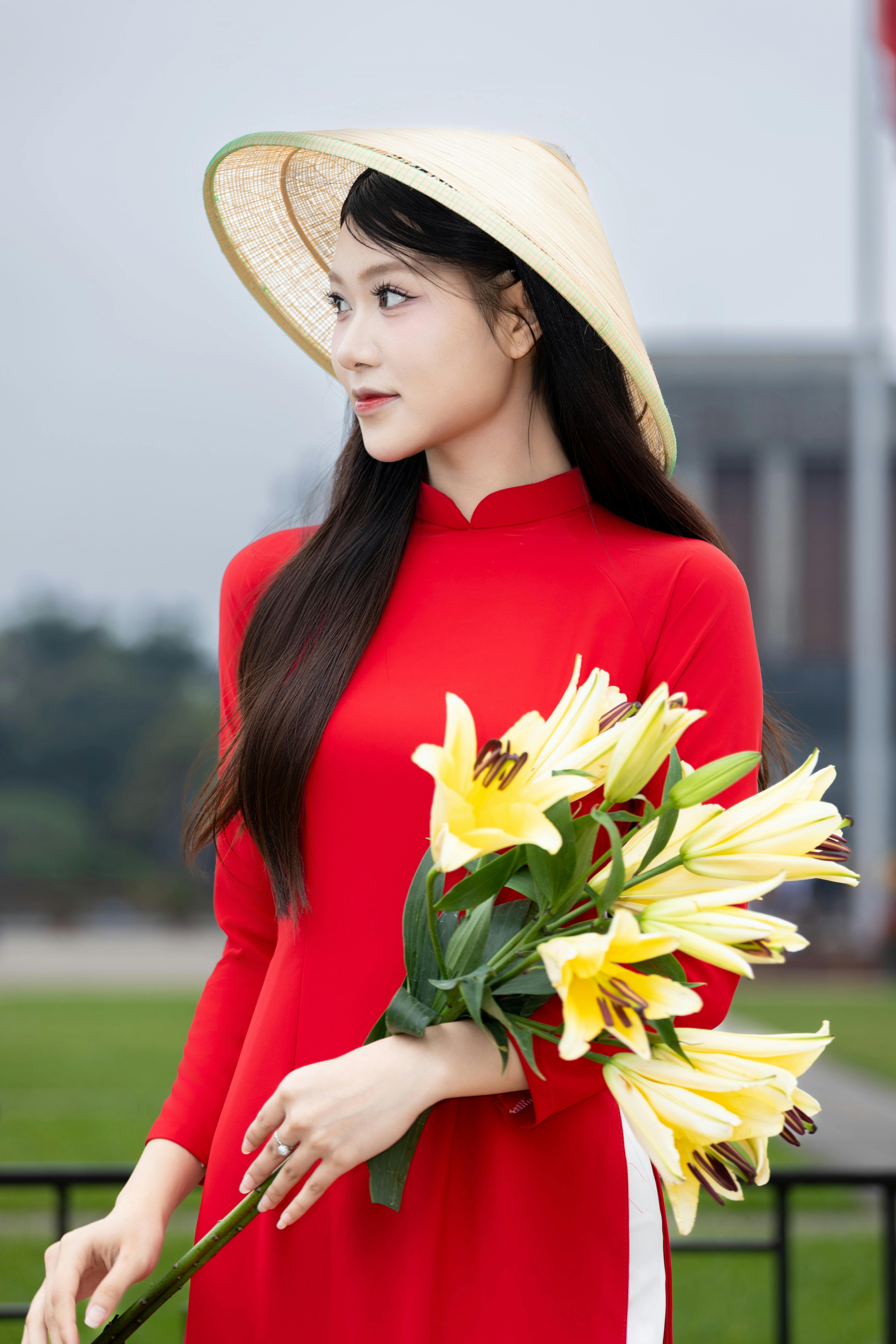 A Vietnamese woman in traditional attire holds a lily bouquet, displaying cultural elegance in Hà Nội.