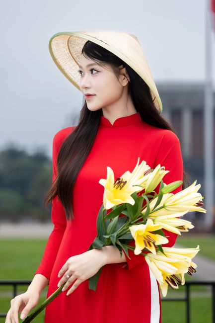 A Vietnamese woman in traditional attire holds a lily bouquet, displaying cultural elegance in Hà Nội.