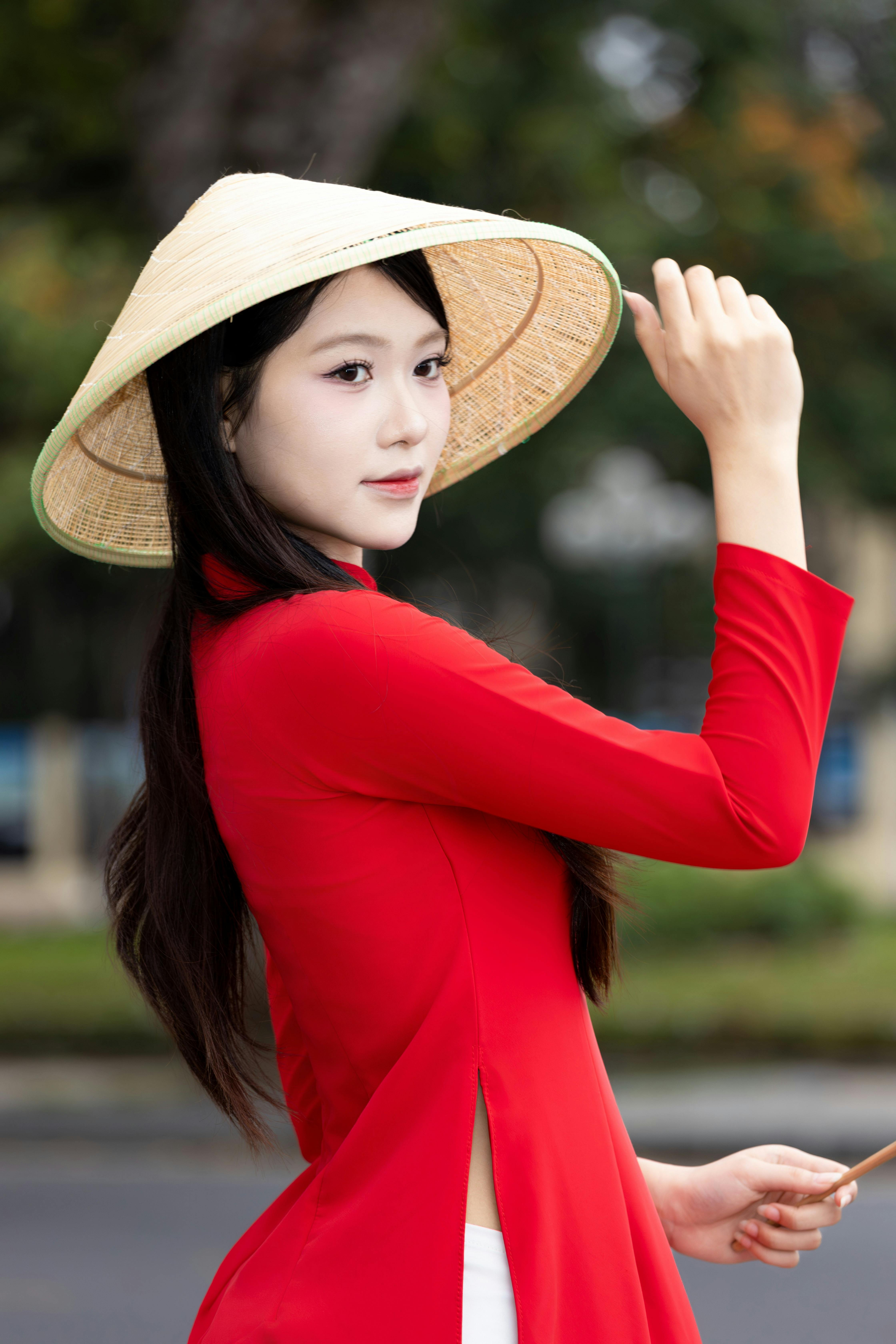 A woman wearing a red ao dai and conical hat, embodying Vietnamese culture in Hanoi.