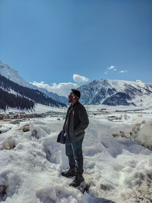 Free A man stands in a snowy landscape with scenic mountain views in Gulmarg. Stock Photo