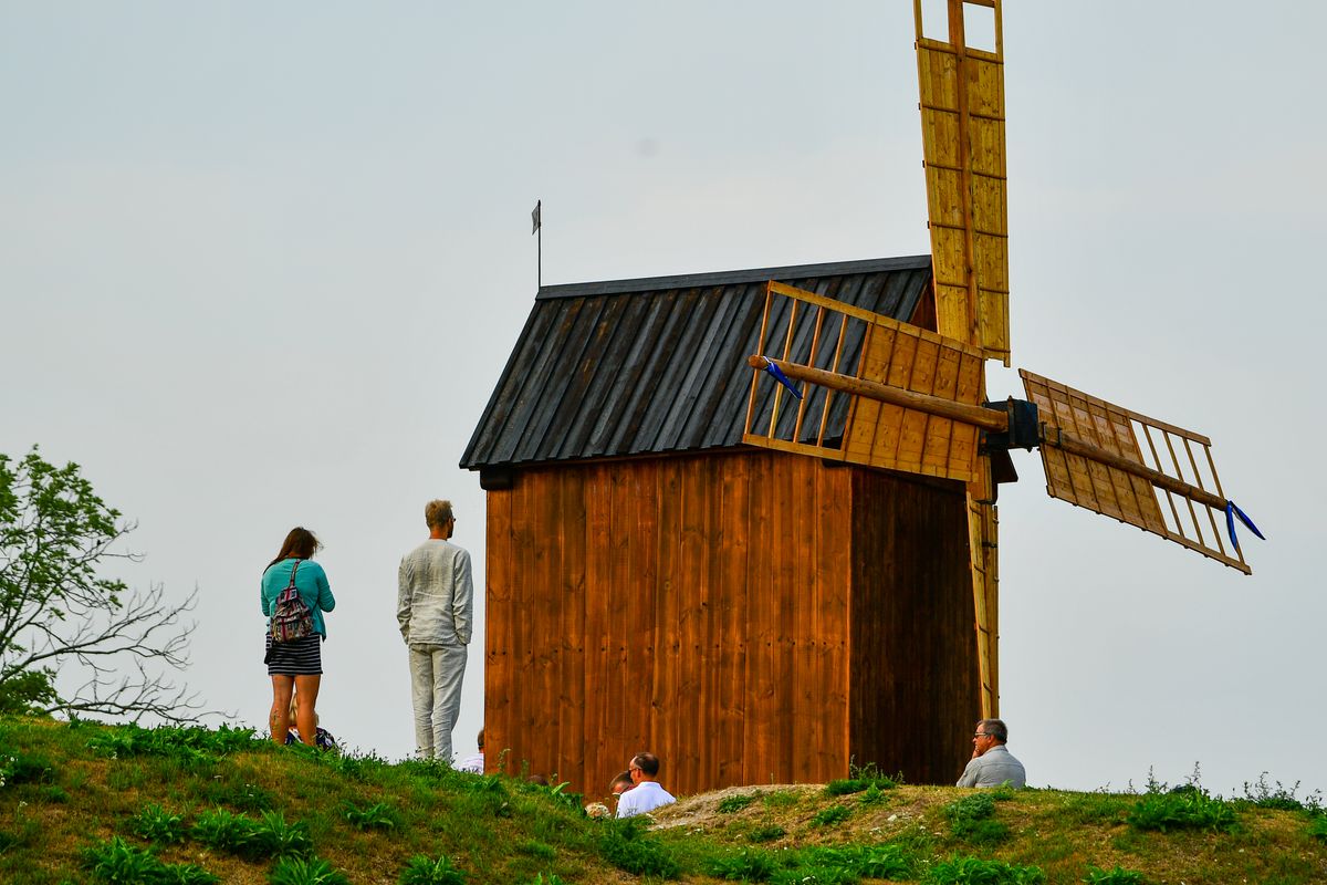 Vizitatori langa o moara de vant de lemn in Saaremaa
