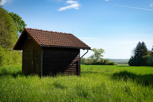 Free A charming wooden hut amidst lush green fields under a clear blue sky in Ölbronn-Dürrn, Germany. Stock Photo