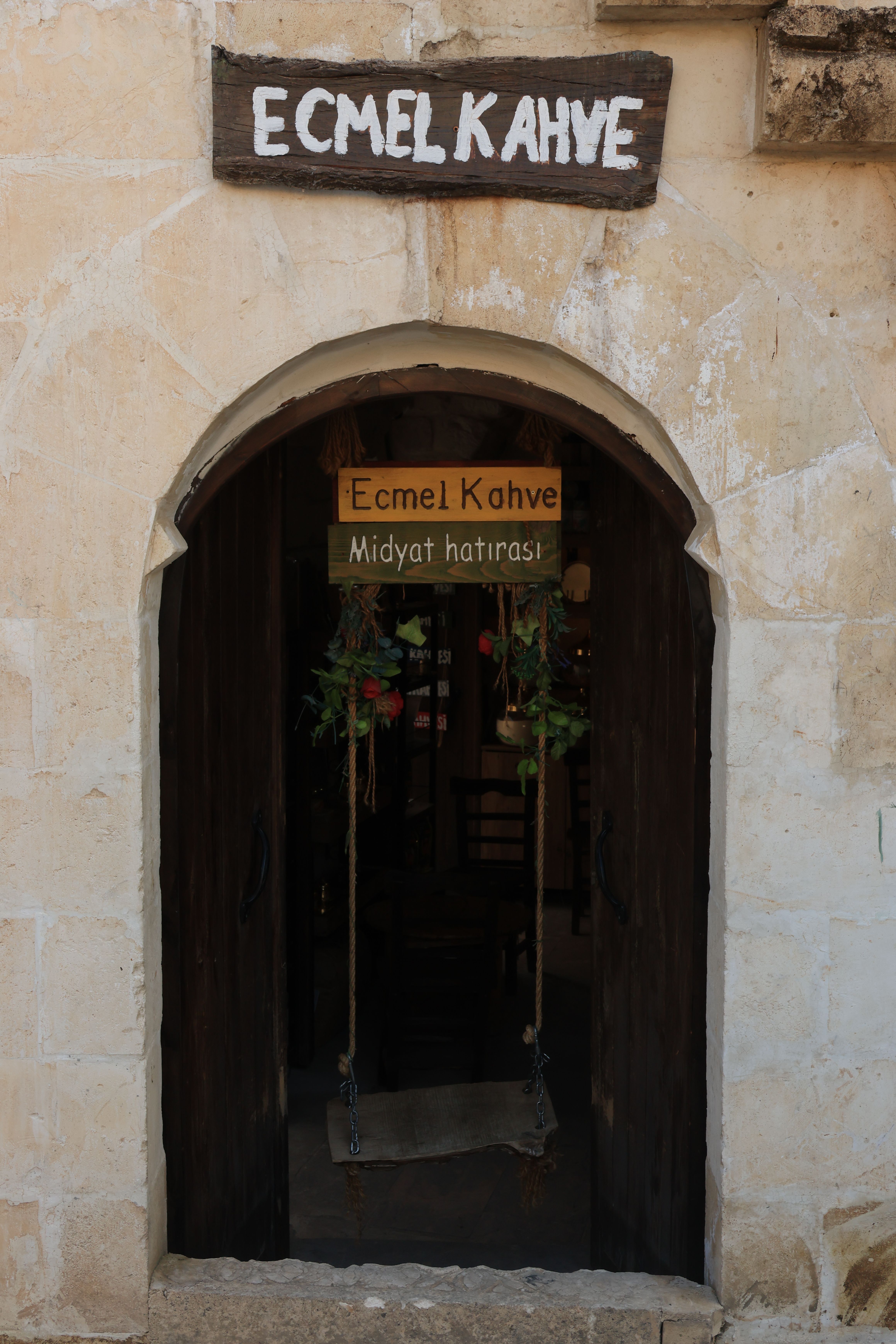 A rustic entrance to Ecmel Kahve in Midyat, showcasing classic architecture.
