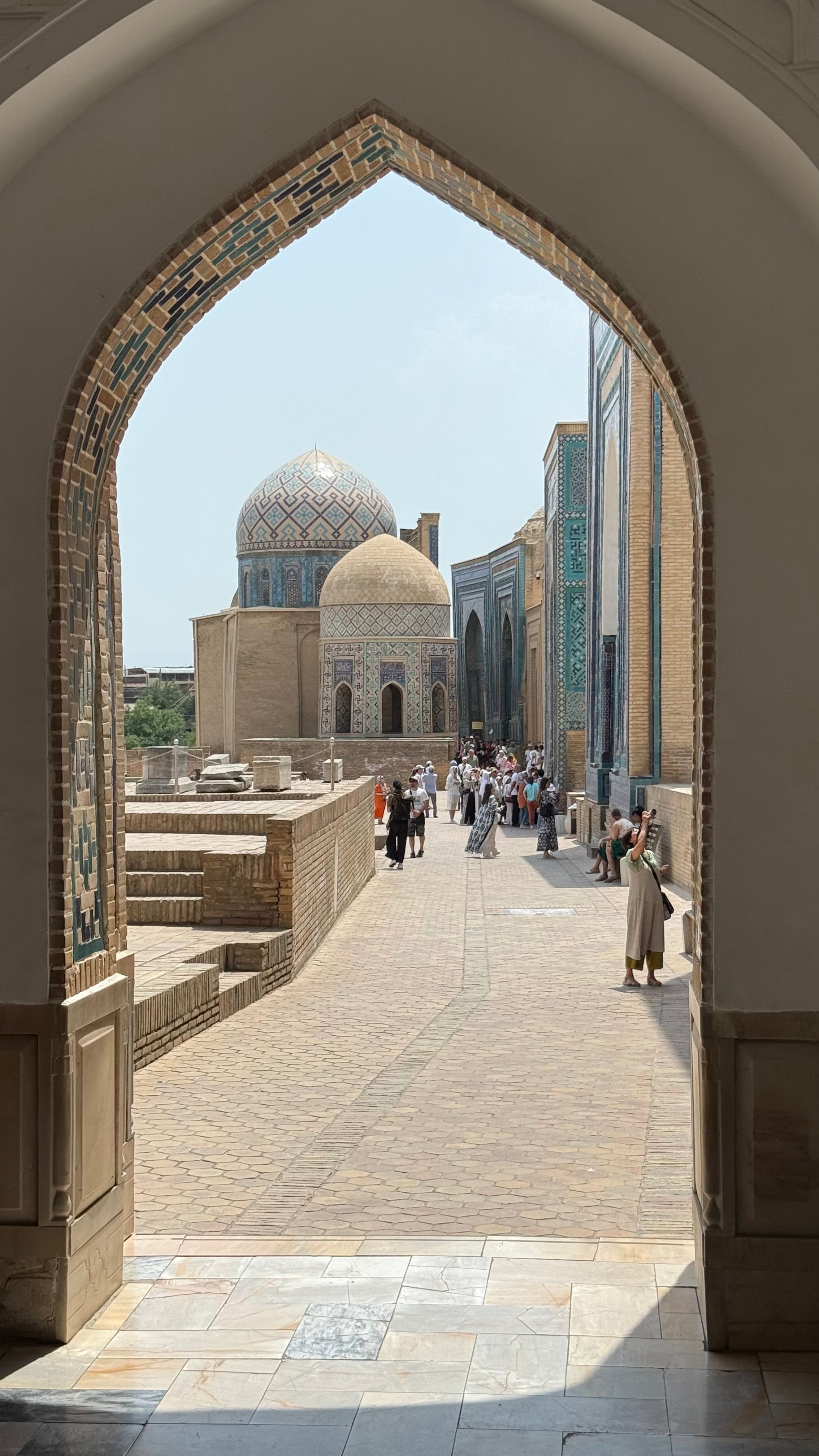 A view through an archway of a historic site in Samarkand with people exploring the area.
