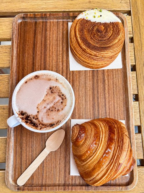 Free A cup of hot coffee with pastries on a wooden tray, perfect for a cozy cafe experience. Stock Photo