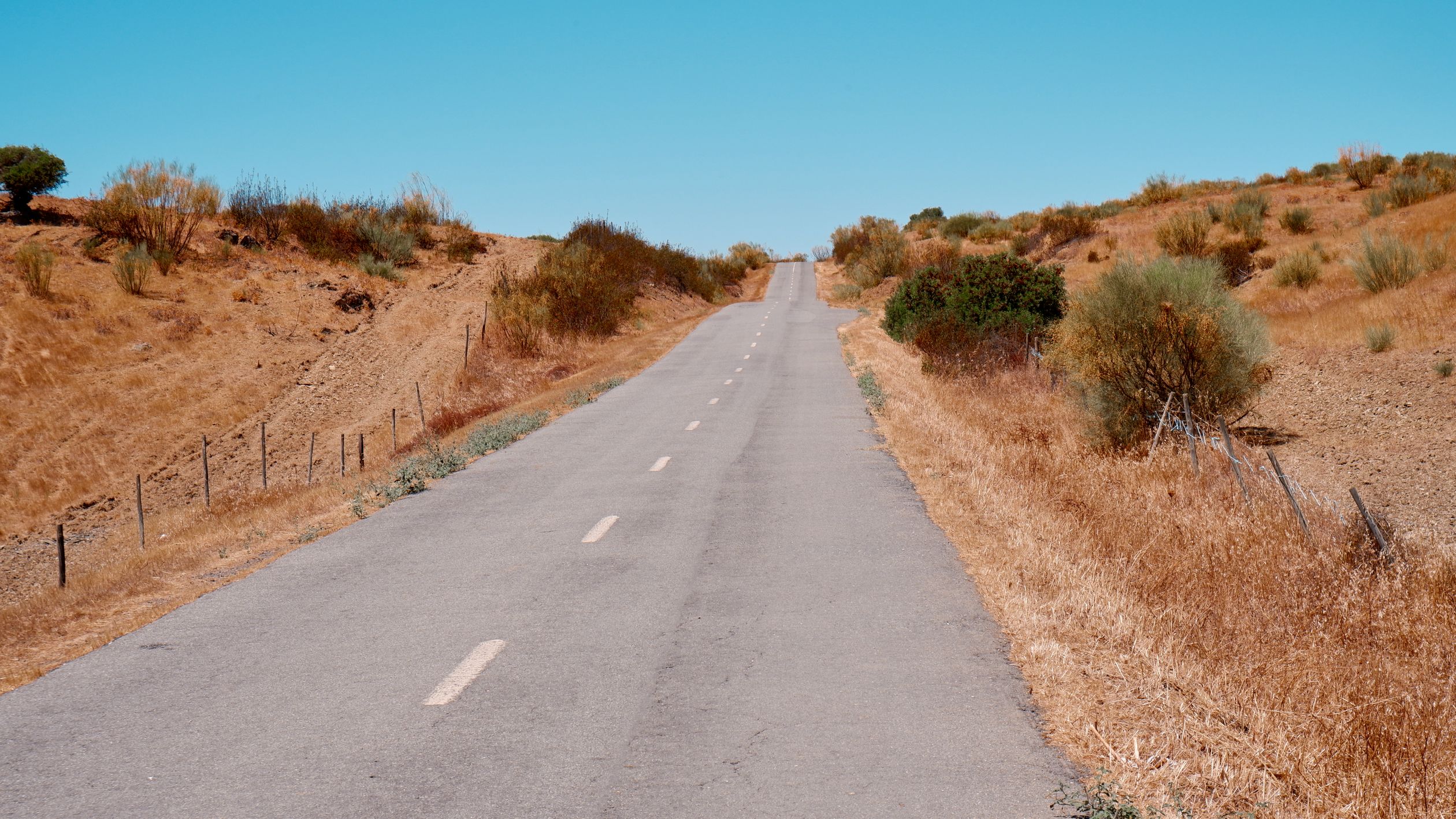 A serene, open road in the dry landscape of Portugal, ideal for summer road trips.