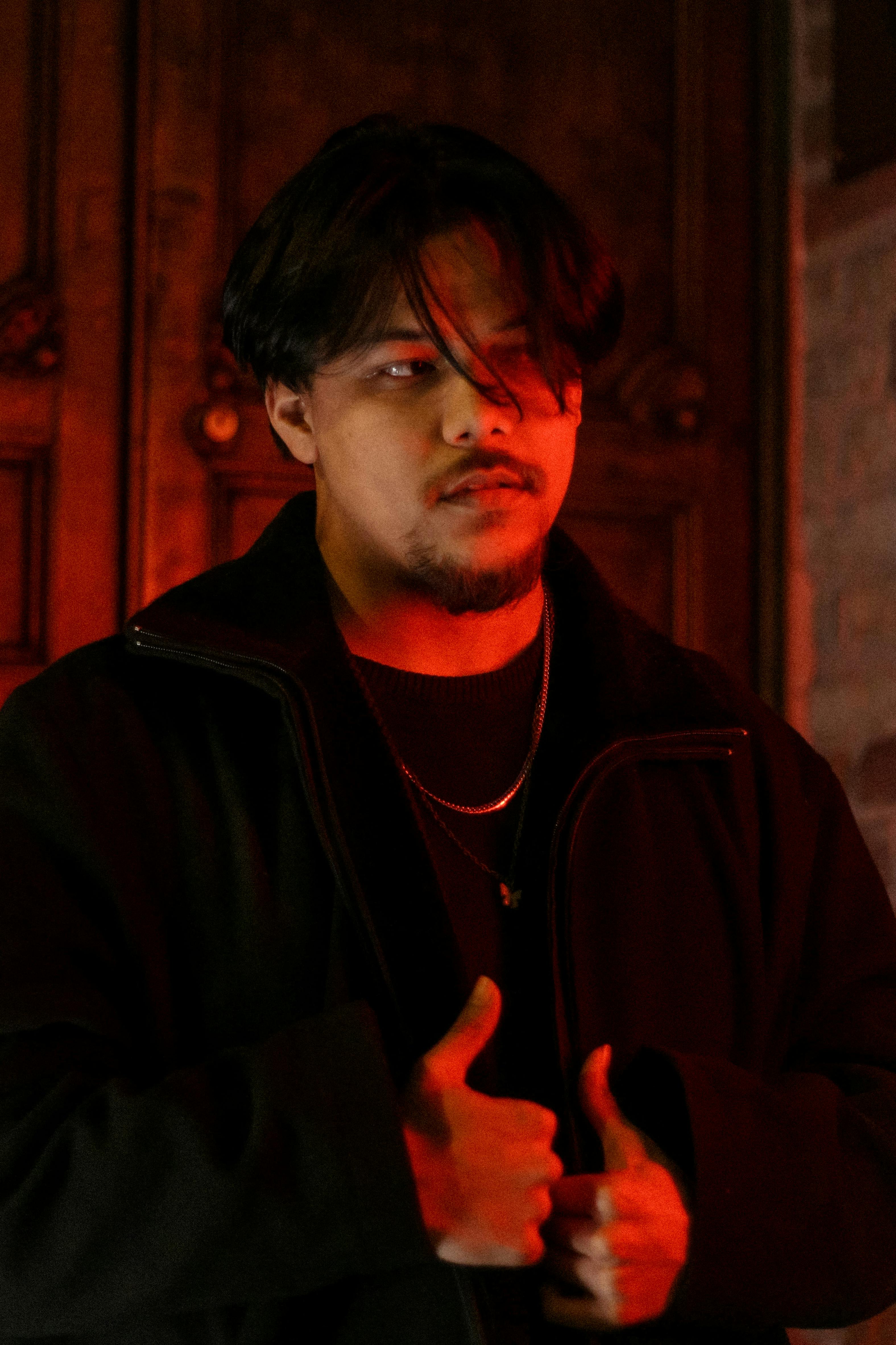 A compelling portrait of a man with dramatic red lighting, highlighting his face and expression indoors.