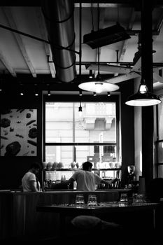 Monochrome cafe scene featuring baristas working at a coffee bar.