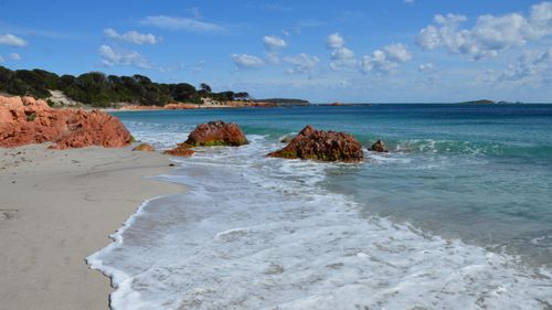Free Beautiful beach scene in Porto-Vecchio, Corse, France featuring red rocks and calm waves. Stock Photo