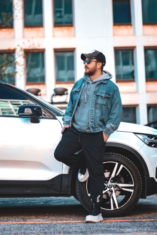 Free Man in casual wear leaning on a stylish car in an urban setting. Stock Photo