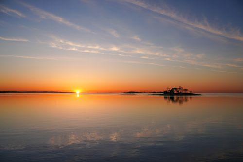 Free A breathtaking sunrise over a calm sea with an isolated island silhouette. Stock Photo