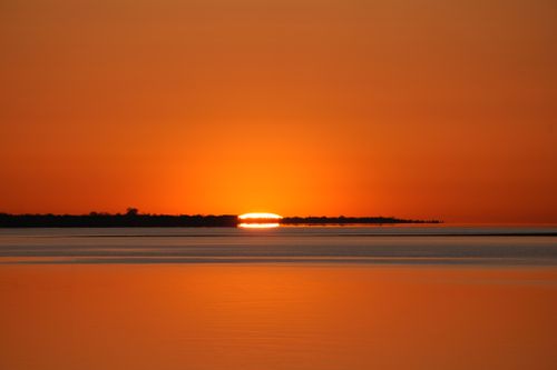 Free Stunning orange sunset over tranquil water creates a serene and peaceful atmosphere. Stock Photo
