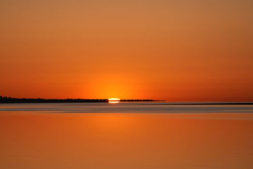 Free A breathtaking orange sunset reflecting on calm waters, creating a serene and peaceful scene. Stock Photo