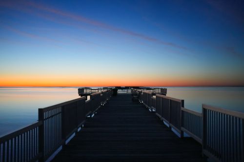 Free Tranquil ocean pier with a vibrant sunrise sky, perfect for peaceful and calming themes. Stock Photo