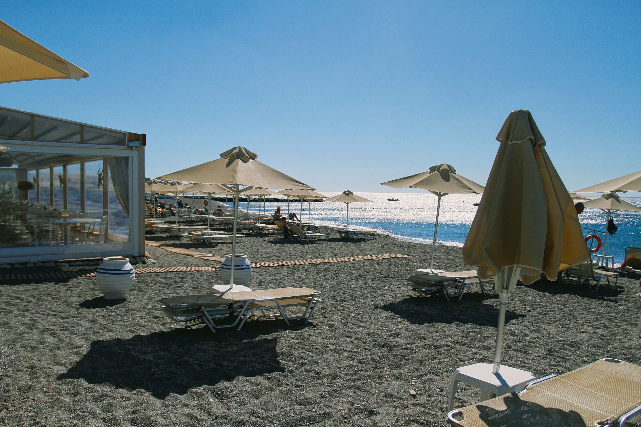 Kamari Santorini black sand beach with tavernas and loungers