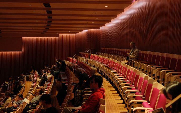 Audience in Sydney Opera House auditorium watching a performance, showcasing modern interior design.
