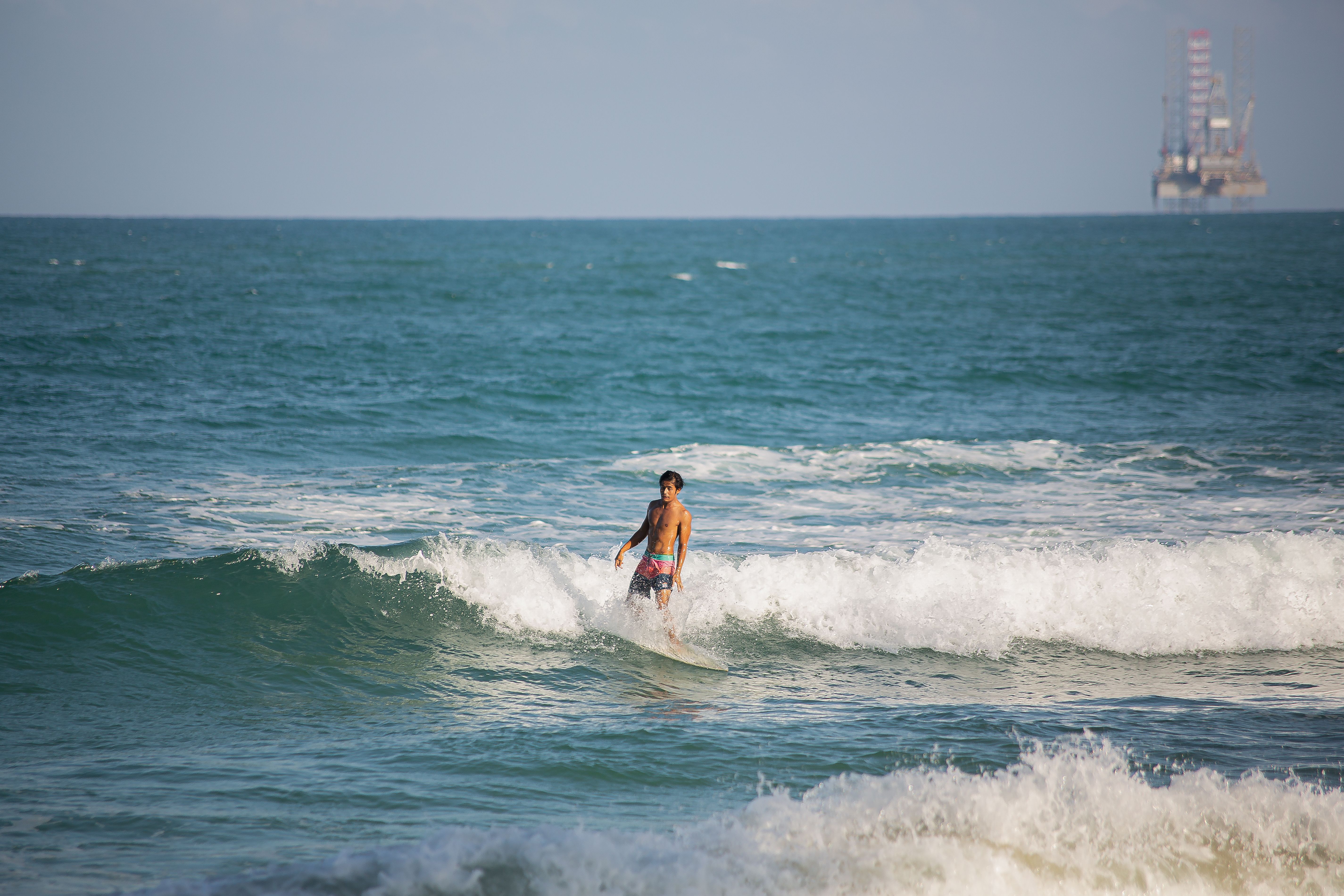 Man Surfing on Ocean Waves with Offshore Rig · Free Stock Photo