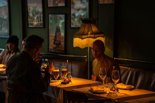 Warm ambiance in a dimly lit restaurant with people enjoying drinks at a table.