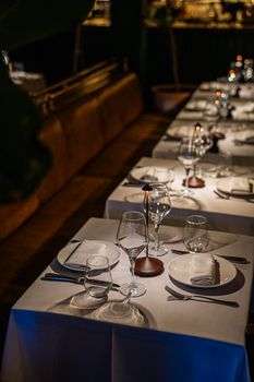 An elegant restaurant table setting with white tablecloths, glassware, and ambient lighting for a cozy dining experience.