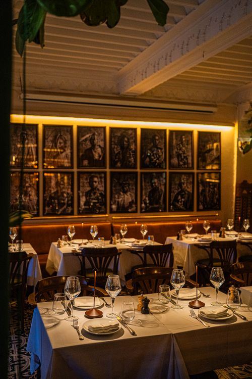 Free Cozy restaurant dining area with elegant table settings and ambient lighting, showcasing artistic photo wall decor. Stock Photo