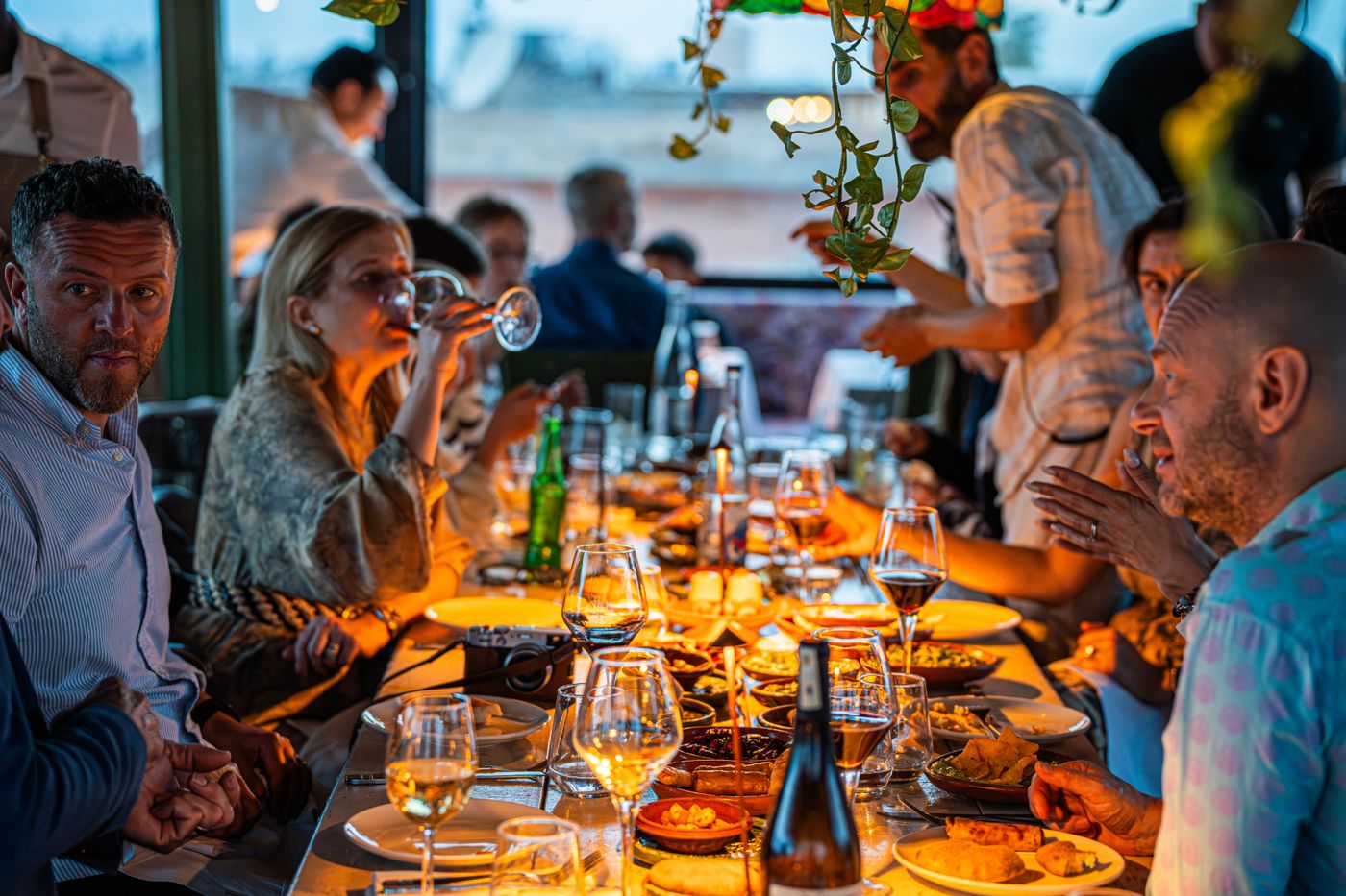 Guests in conversation around a long candlelit dinner table — photo by Le Salama on Pexels