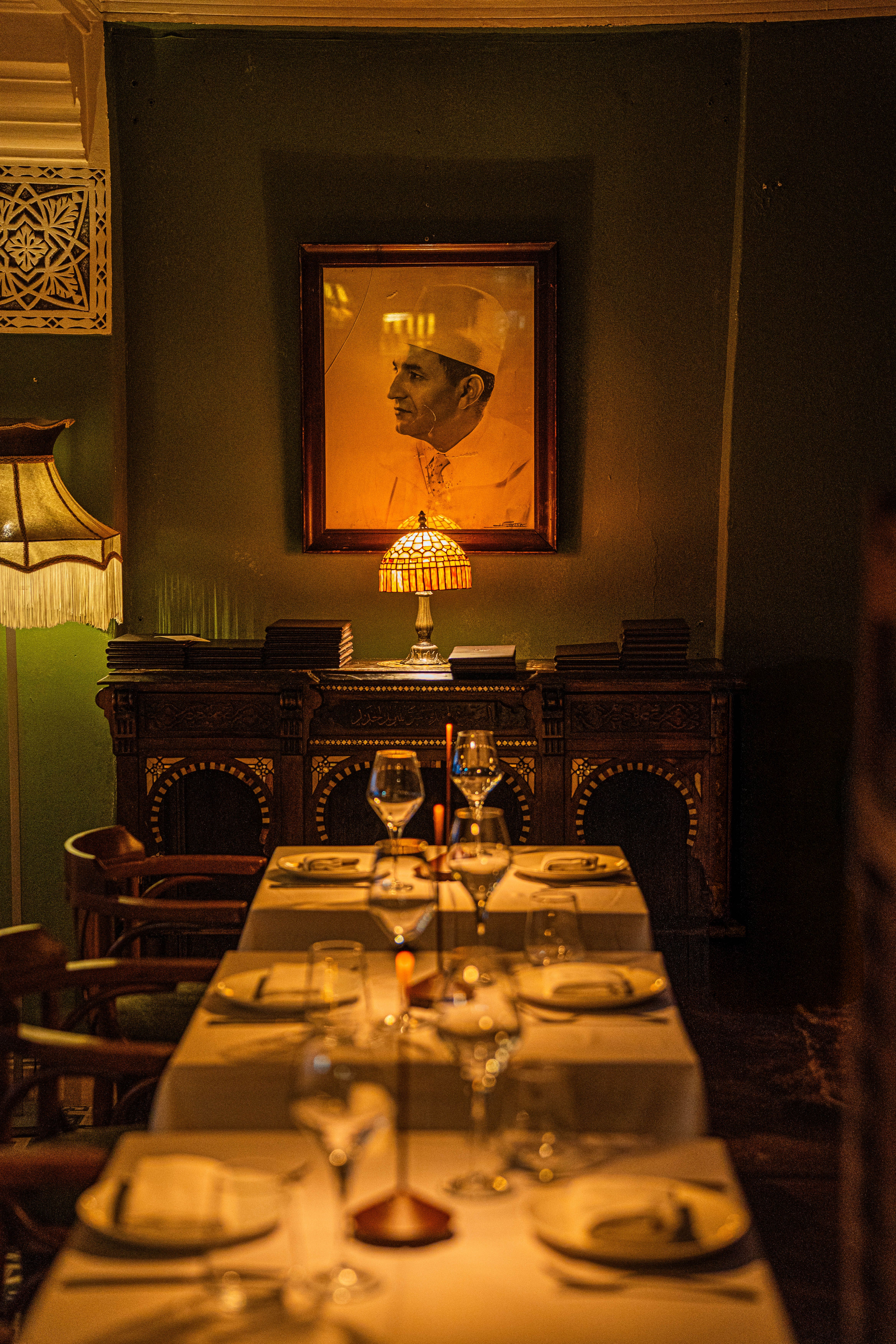 Warmly lit dining room featuring elegant table settings and vintage decor, perfect for a cozy atmosphere.