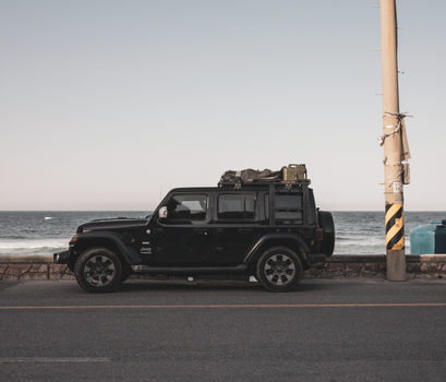 A rugged SUV parked near the ocean, ready for an adventure trip along the coastline.