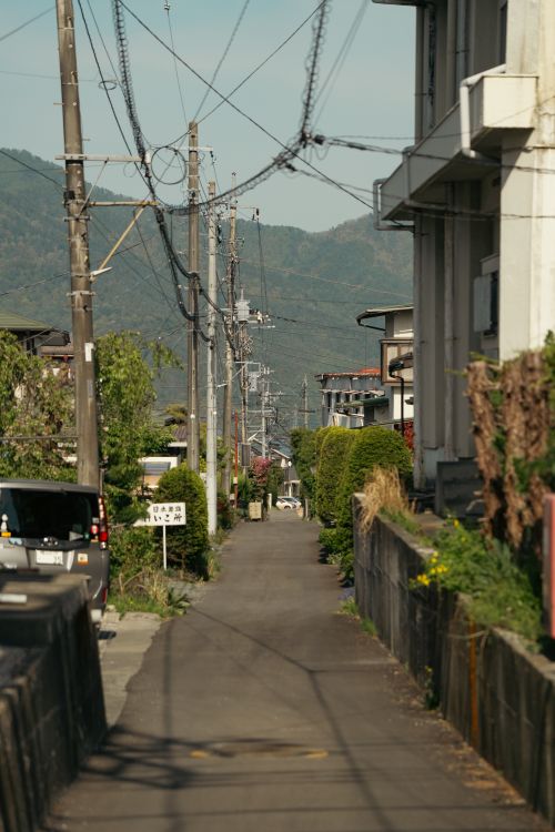 Free Tranquil Japanese residential street scene with power lines and mountain backdrop, capturing daily life vibes. Stock Photo