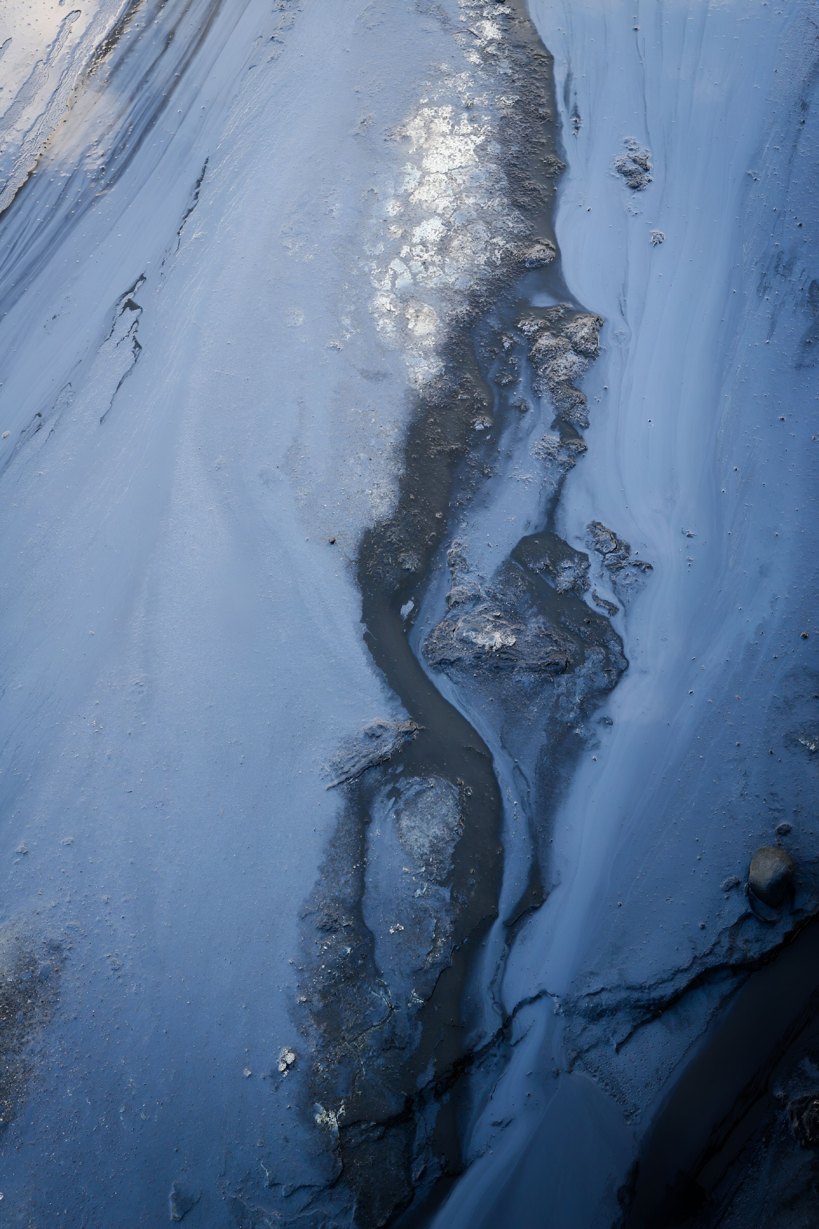 Aerial shot of a winding muddy riverbed creating abstract natural patterns.