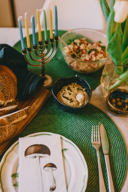 A beautifully arranged Hanukkah table with menorah, challah, hummus, and olives, perfect for a festive celebration.