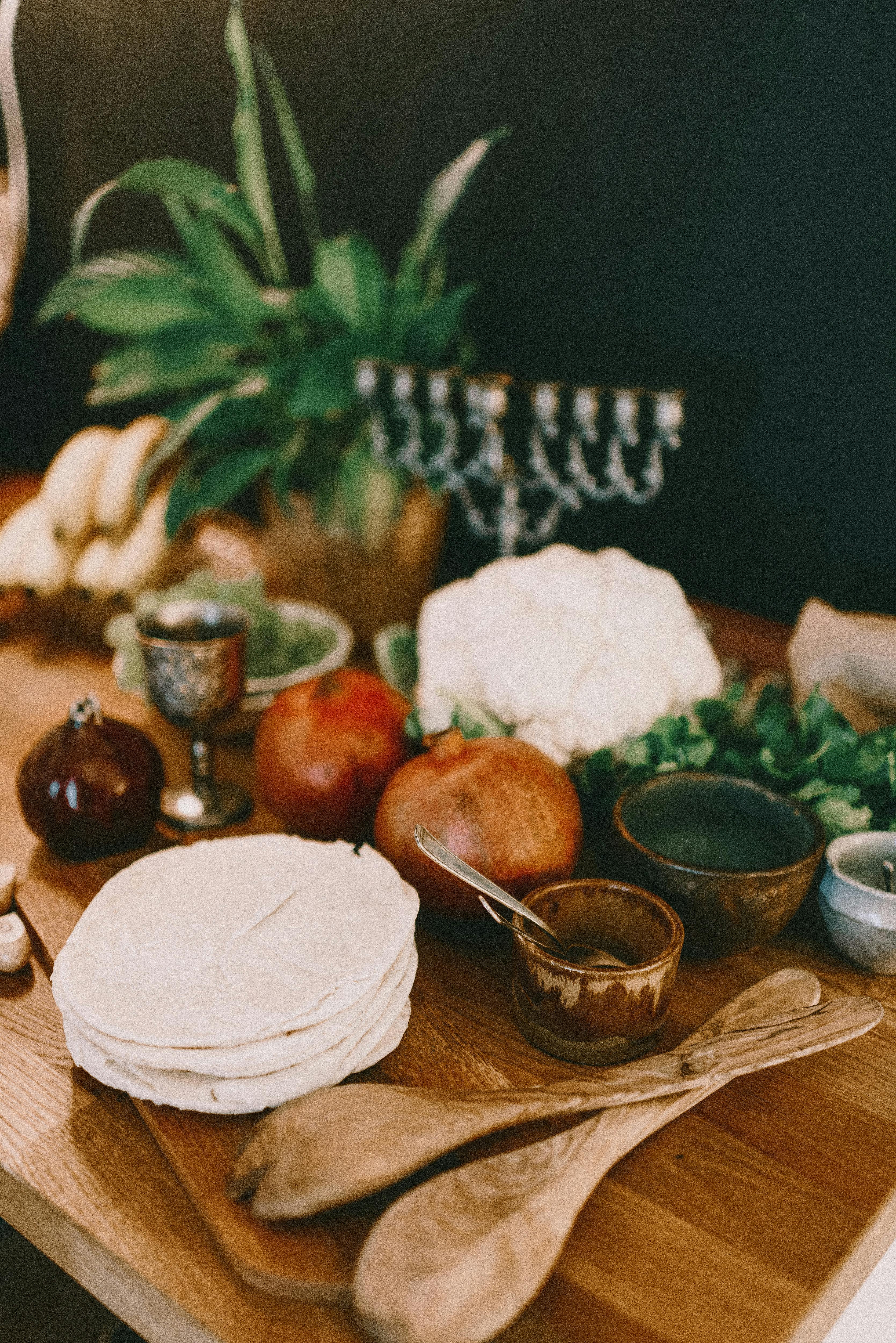 A traditional Jewish table setting with pomegranates, pita, and lush greenery.