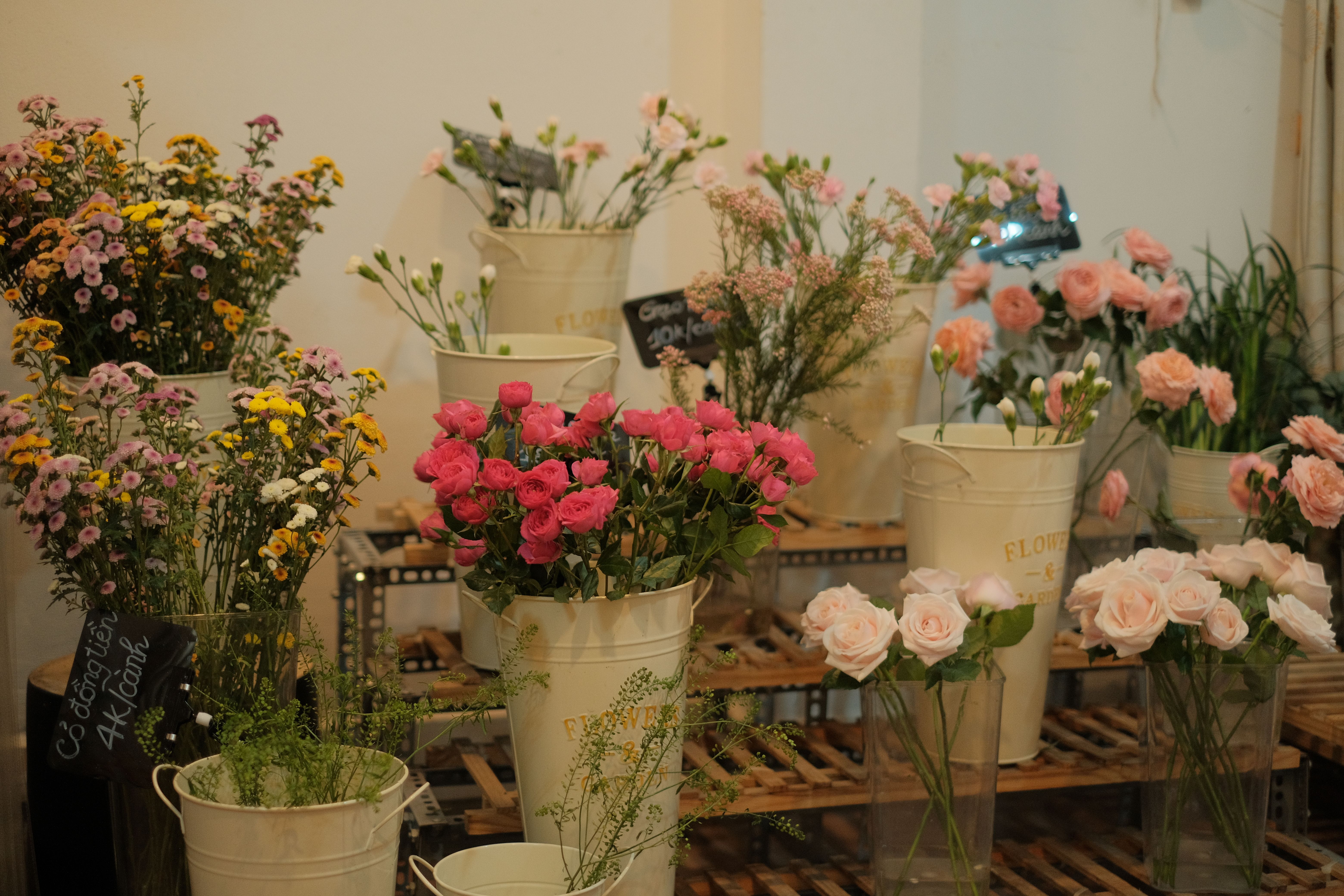 Vibrant flowers in rustic buckets showcased inside a cozy floral shop.