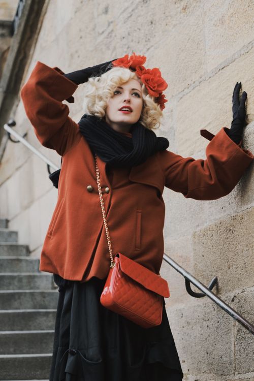Free Stylish woman in red coat and accessories posing by a stone wall staircase. Stock Photo