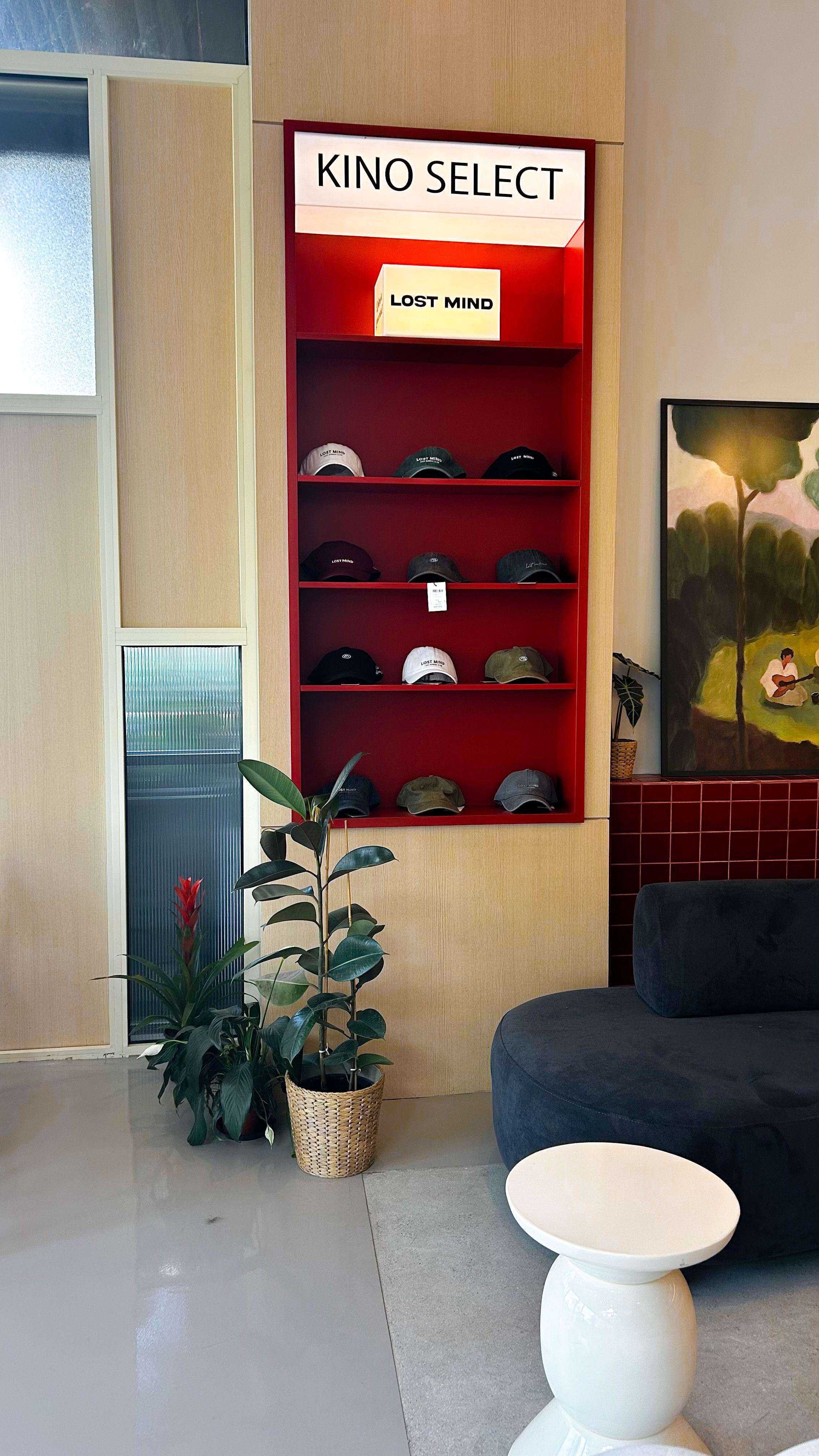 Stylish interior featuring a red shelving unit with hats, modern furniture, and wall art.