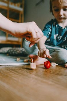 A child plays a traditional dreidel game during Hanukkah celebration inside a cozy room.