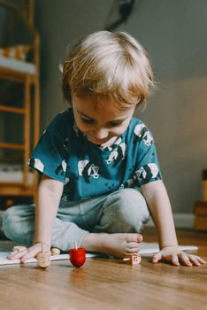 A young child engrossed in playing dreidels at home. Celebrating Hanukkah traditions.
