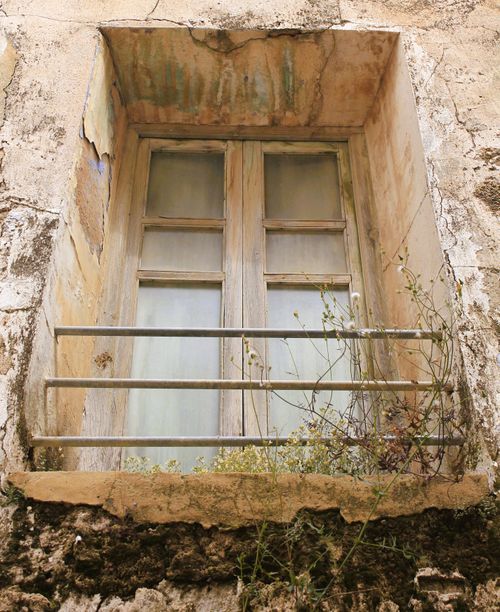 Free A rustic window set in a weathered facade with natural plant growth, portraying decay and history. Stock Photo