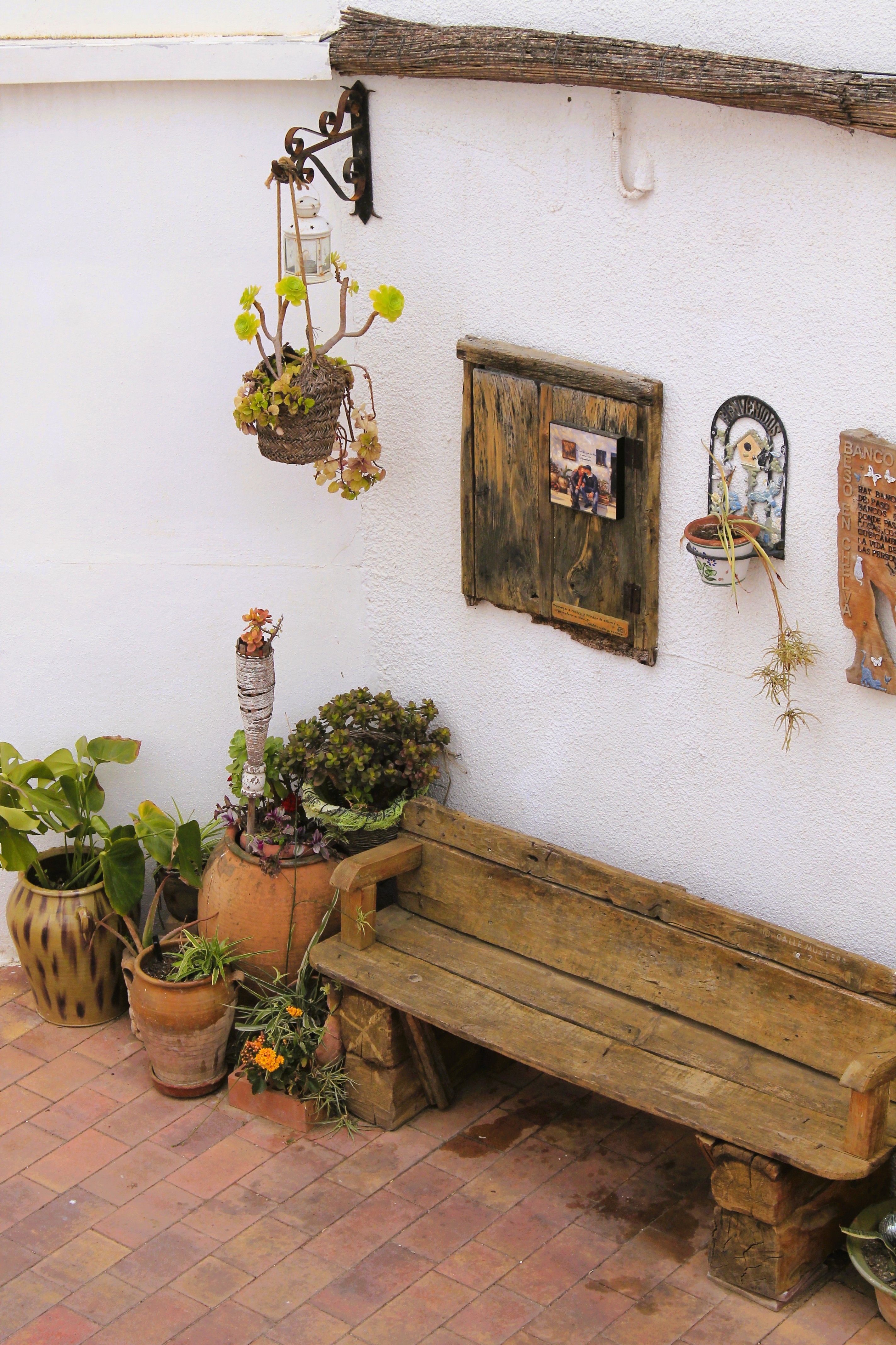 Painted repurposed terra cotta pots arranged on a small budget patio with herbs and flowers