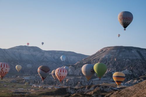 Free Majestic view of colorful hot air balloons flying over Cappadocia's unique landscape at sunrise. Stock Photo
