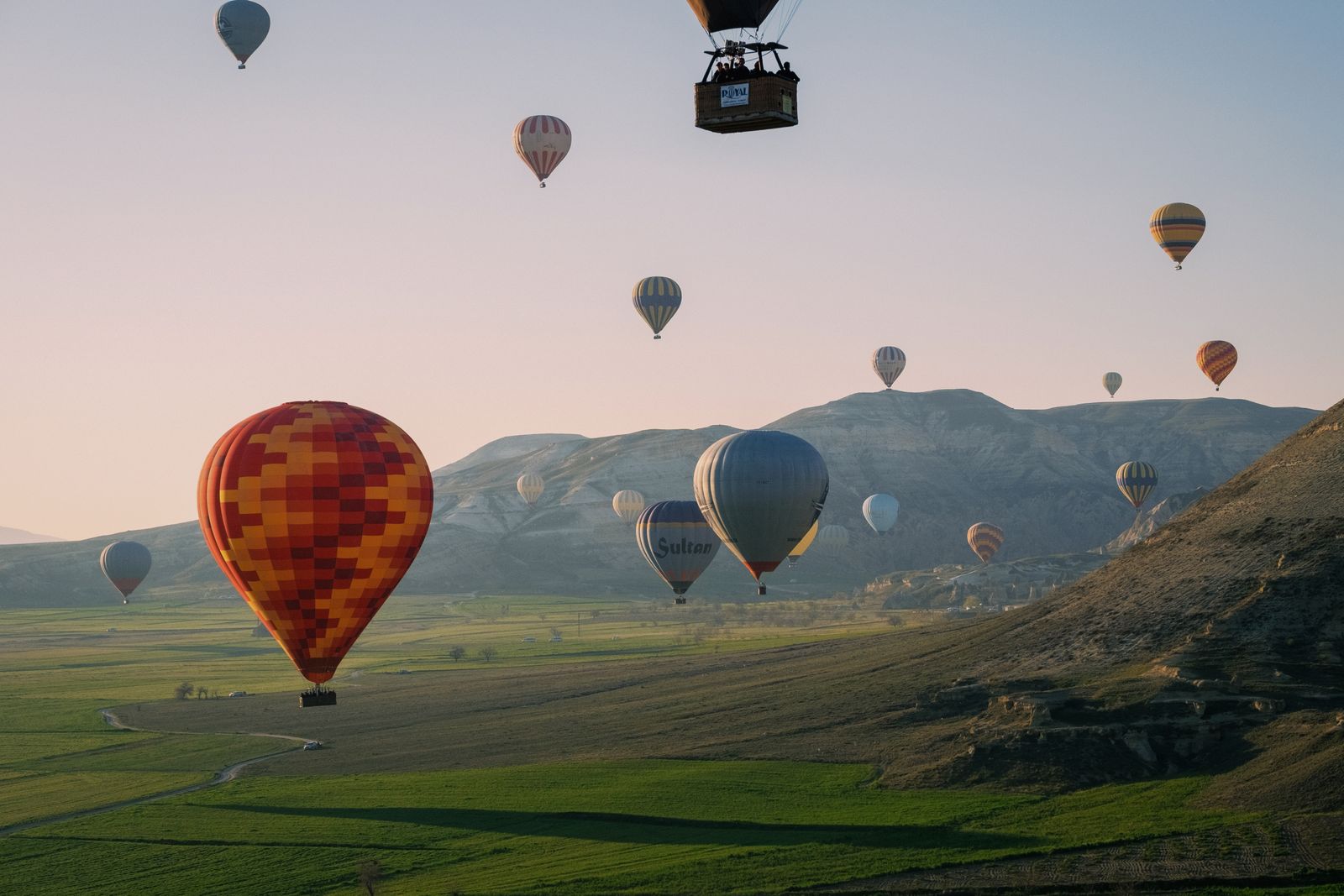 Hot air balloons float over Cappadocia's unique landscape at sunrise, offering a serene and picturesque view.